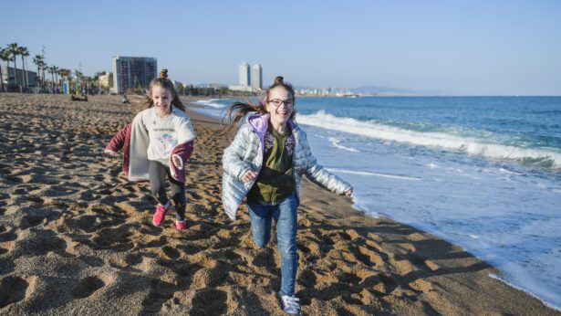 Niños corriendo contentos en playa de Barcelona